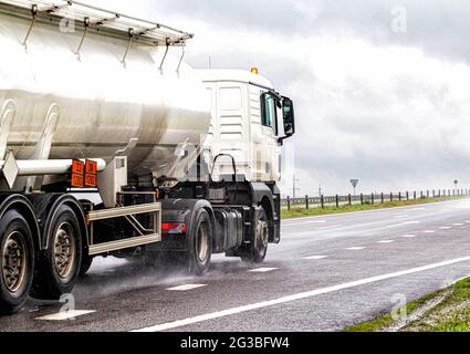 Un tracteur semi-rail blanc équipé d'un camion-citerne en acier inoxydable transporte des marchandises dangereuses sur la route. Transport Kotsnet d'huile moteur et de carburant diesel Banque D'Images