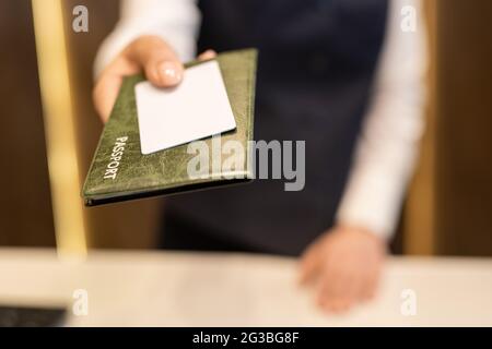 Main de la réceptionniste qui passe le passeport et la carte blanche en plastique vierge Banque D'Images