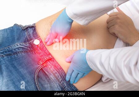 Le chirurgien effectue un examen du doigt d'un patient qui a de la douleur autour du nombril. Concept de la hernie ombilicale, élimination de la hernie ombilicale, clos Banque D'Images