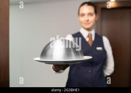 Plateau avec petit déjeuner tenu par une jeune femme femme de chambre en uniforme Banque D'Images