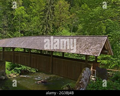 Passerelle couverte en bois traversant une rivière dans la célèbre gorge de Wutach ('Wutachschlucht') dans le sud de la Forêt-Noire, en Allemagne entourée d'une forêt dense. Banque D'Images