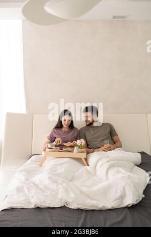 Jeune couple prenant le petit déjeuner au lit après le sommeil Banque D'Images