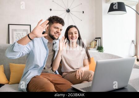 Un jeune couple heureux communique par chat vidéo devant un ordinateur portable Banque D'Images