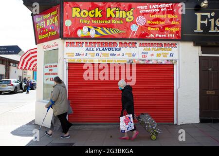 Les personnes âgées marchent à côté de la boutique Rock King qui vend du Rock à Filey, dans le nord du Yorkshire. Filey est une ville côtière sur la côte nord-est o Banque D'Images