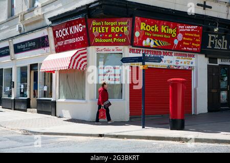 Une femme marche dans la boutique Rock King qui vend des Rock à Filey, dans le nord du Yorkshire. Filey est une ville côtière sur la côte nord-est de Yworks Banque D'Images