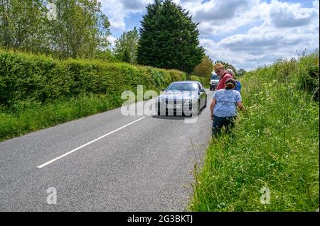 Un groupe de randonneurs se tenant sur le bord de l'herbe tandis que la circulation passe le long de South Road entre Plumpton Green et South Chailey, East Sussex, Engl Banque D'Images