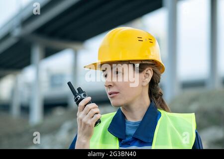 Une femme inspecteur ou un ingénieur utilisant un talkie-walkie pendant qu'elle travaille sur le chantier Banque D'Images
