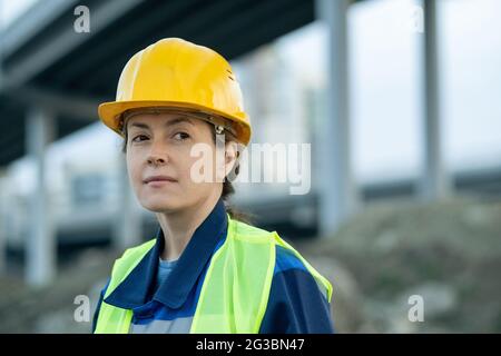 Jeune femme constructeur en casque et uniforme sur le chantier de construction Banque D'Images
