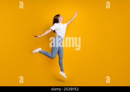 Pleine longueur photo de taille de corps de fille insouciante avec les cheveux longs saut de la main vers le haut imaginez isolé sur fond jaune clair de couleur Banque D'Images