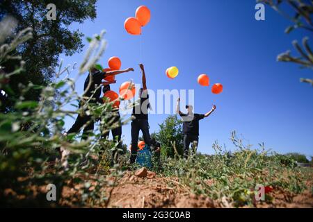 Les Palestiniens masqués lancent des ballons incendiaires de la bande de Gaza vers Israël. Des militants palestiniens lancent des ballons incendiaires depuis la bande de Gaza vers Israël pour protester contre la marche du drapeau qui se déroule actuellement à Jérusalem-est et les inquiétudes d'une nouvelle flambée de violence alors que quelque 5,000 nationalistes de droite doivent défiler dans la vieille ville de Jérusalem en signe de drapeau bleu et blanc d'Israël. Des ballons incendiaires de Gaza ont brûlé des terres agricoles dans au moins 13 endroits différents, rapporte les médias israéliens. (Photo d'Ahmed Zakot/SOPA Images/Sipa USA) Banque D'Images