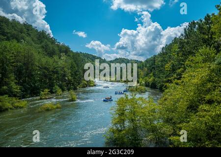 Plusieurs groupes de personnes dans de grands radeaux allant rafting en eau vive sur la rivière Ocoee dans le Tennessee approchant les rapides dans la distance sur un vif Banque D'Images