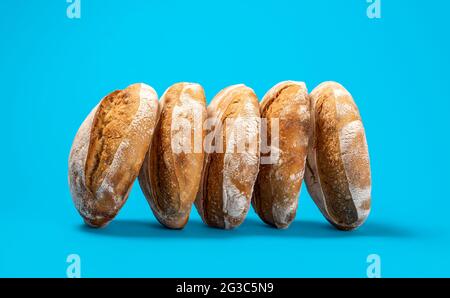 Délicieux pains de levain isolés sur fond bleu. SideView avec quelques pains faits maison sur une table bleue. Banque D'Images