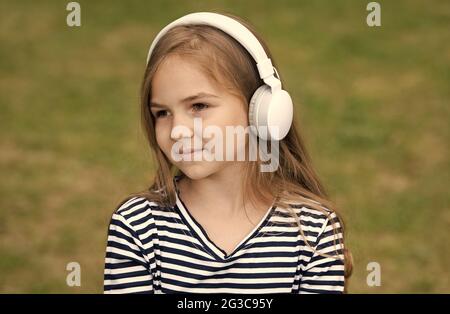 Mignon petit enfant écouter le cours de langue audio dans les écouteurs en extérieur, l'anglais Banque D'Images