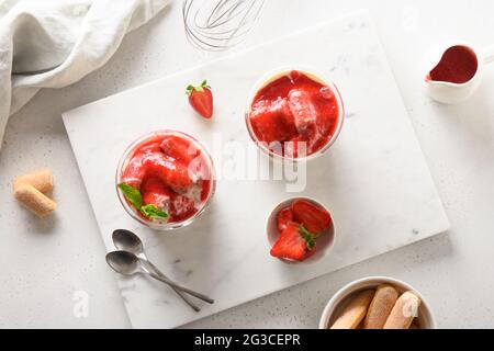 Dessert aux fraises avec biscuit savoyardi, mascarpone et crème fouettée décoré de fraises sur fond blanc. Vue de dessus. Italien TI Banque D'Images