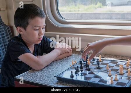 Jeunes garçons jouant aux échecs près de la fenêtre dans le train Banque D'Images
