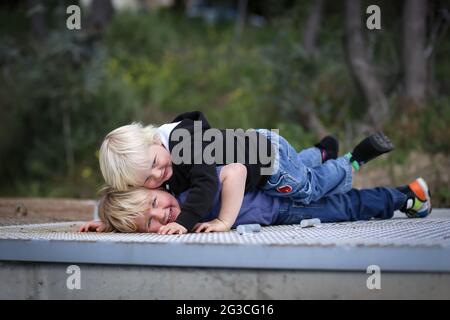 De jolis garçons blonds australiens couchés les uns sur les autres sur le toit - le concept de fraternité Banque D'Images