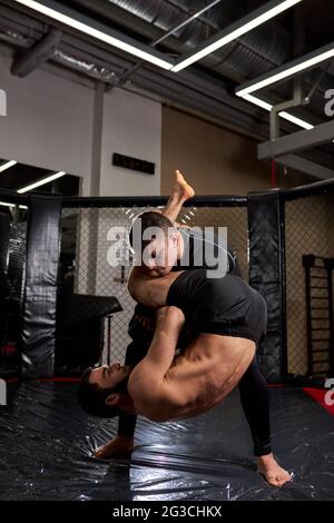 Sport concept de combat sans règles. Deux lutteurs d'athlète à la salle de gym, s'entraîner ensemble. Combats sans règles de boxe MMA. Combats sportifs vue latérale Banque D'Images