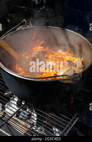 Cuisson de pilaf oriental traditionnel dans un chou-fleur au feu. De gros morceaux de viande et des oignons et carottes finement hachés sont cuits sur du charbon de bois. Zer Banque D'Images