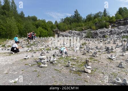 Ruskeala, Russie - 12 juin 2021 : les touristes construisent la pierre de cairns dans une ancienne carrière de marbre dans le parc de montagne de Ruskeala Banque D'Images