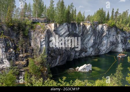 Ruskeala, Russie - 12 juin 2021 : ancienne carrière de marbre remplie d'eau souterraine. Paysage de Karelian avec des touristes en bateaux et sur une côte rocheuse Banque D'Images