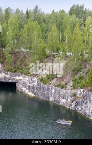 Ruskeala, Russie - 12 juin 2021 : les touristes naviguent dans un bateau à travers une ancienne carrière de marbre remplie d'eau souterraine. Photo verticale Banque D'Images