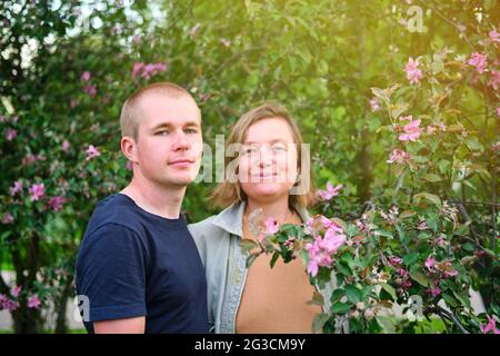 Couple heureux sur le fond d'un arbre de printemps en pleine floraison dans le parc Banque D'Images