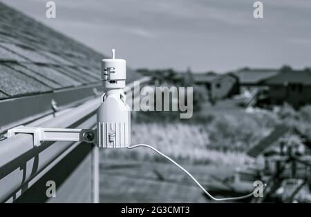 Détecteur de pluie sprinkleur sans fil utilisé pour économiser l'eau. Le dispositif est installé sur une gouttière de toit résidentielle Banque D'Images