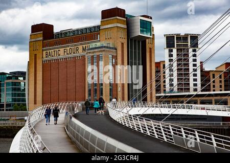 Les gens marchent à travers le High Gateshead Millennium Bridge qui relie Gateshead à Newcastle en traversant la rivière Tyne avec le Baltic Flour Mills Art Galle Banque D'Images