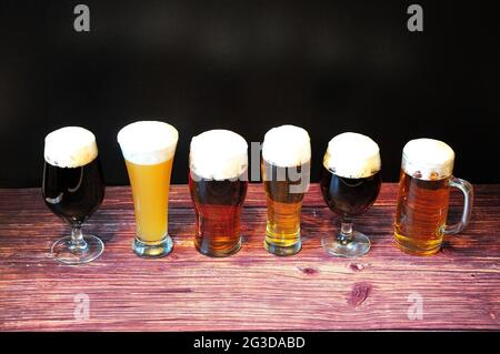 Six verres différents avec différents types de bière sont dans une rangée sur une table en bois. Gros plan. Banque D'Images