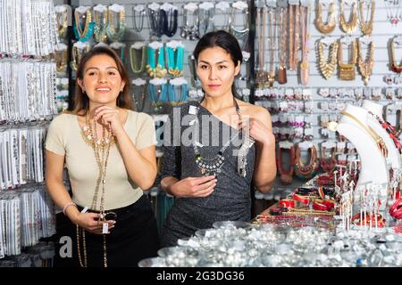 Deux femmes heureuses choisissent différents bijoux dans magasin de bijoux Banque D'Images