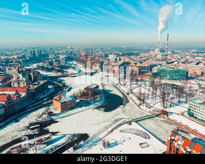 Wroclaw, Pologne 02.15.2021 - Paysage industriel enneigé avec bâtiments historiques. Cheminées de la centrale thermique en arrière-plan. Fumée polluant le ciel bleu clair. Banque D'Images