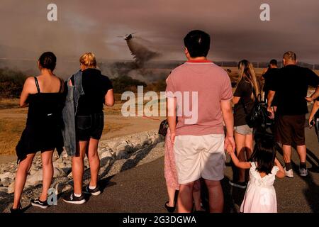 Los Angeles, Californie, États-Unis. 15 juin 2021. Les gens regardent comme un hélicoptère largue de l'eau au feu de broussailles brûlant dans le secteur de loisirs du barrage de Santa Fe, à Irwindle, en Californie, le mardi 15 juin, 2021. Credit: Ringo Chiu/ZUMA Wire/Alay Live News Banque D'Images