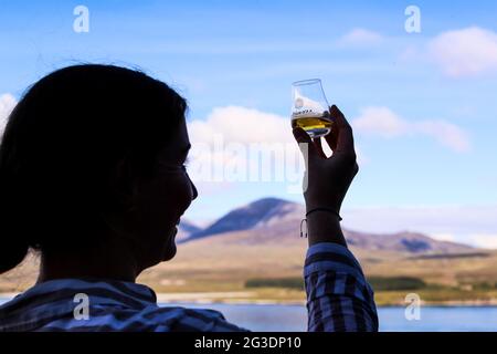 Boire du whisky à la distillerie Ardnahoe sur l'île d'Islay, sur la côte ouest de l'Écosse, avec les Paps du Jura à l'horizon. Banque D'Images