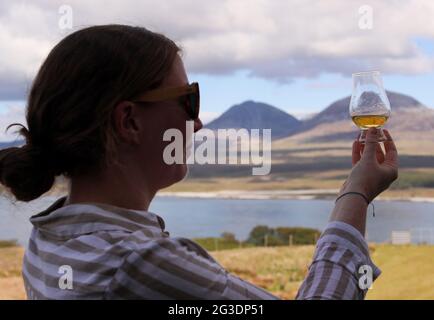 Boire du whisky à la distillerie Ardnahoe sur l'île d'Islay, sur la côte ouest de l'Écosse, avec les Paps du Jura à l'horizon. Banque D'Images