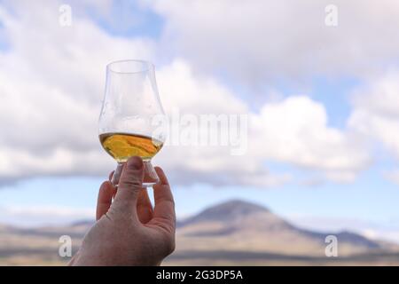 Boire du whisky à la distillerie Ardnahoe sur l'île d'Islay, sur la côte ouest de l'Écosse, avec les Paps du Jura à l'horizon. Banque D'Images