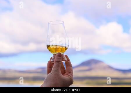 Boire du whisky à la distillerie Ardnahoe sur l'île d'Islay, sur la côte ouest de l'Écosse, avec les Paps du Jura à l'horizon. Banque D'Images