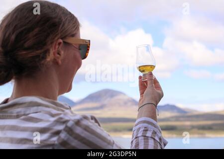 Boire du whisky à la distillerie Ardnahoe sur l'île d'Islay, sur la côte ouest de l'Écosse, avec les Paps du Jura à l'horizon. Banque D'Images