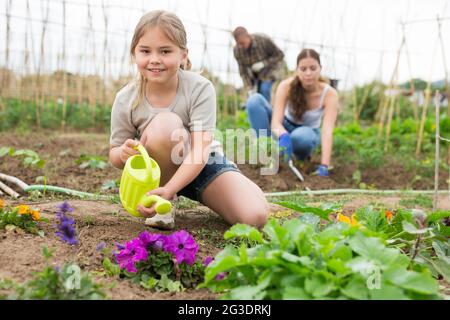 Fille aide maman à arroser les plantes d'un arrosoir dans le champ de ferme Banque D'Images