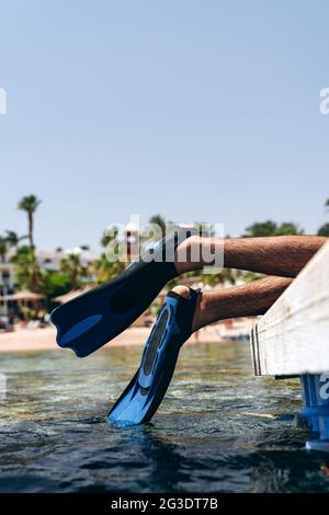 Jambes reposant dans les palmes, touchant l'eau. Repos actif au bord de la mer Banque D'Images