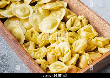 Tortellini et Ravioli faits main à l'italienne, en boîte de bois, sur fond gris Banque D'Images