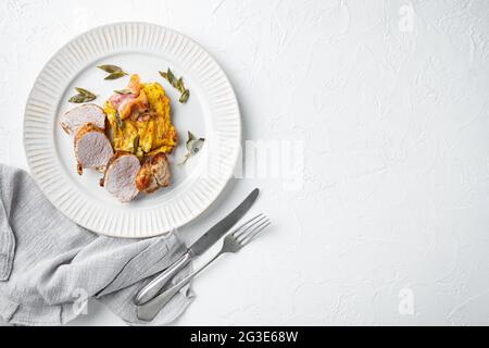 Filet de porc grillé et purée de potatoe gratin avec sauge et prosciutto mis, sur plat, sur fond de pierre blanche, dessus de lit plat, avec copyspace Banque D'Images