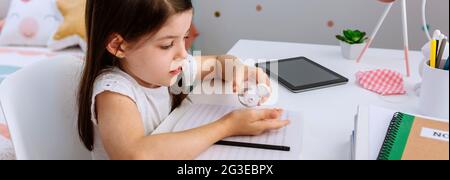 Fille appliquant un désinfectant pour les mains pendant ses devoirs Banque D'Images