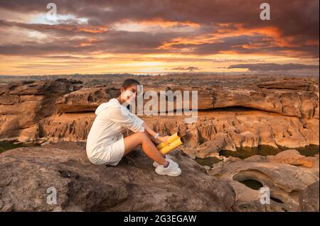 Bonne belle jeune femme asiatique voyageur avec carte papier assis sur la falaise de roche dans le grand canyon de la Thaïlande au coucher du soleil Banque D'Images