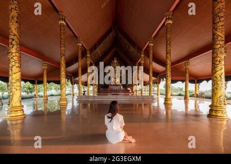 Femme asiatique assise méditation et statue de bouddha d'or dans l'église bouddhiste à Wat sirindhorn wararam Banque D'Images