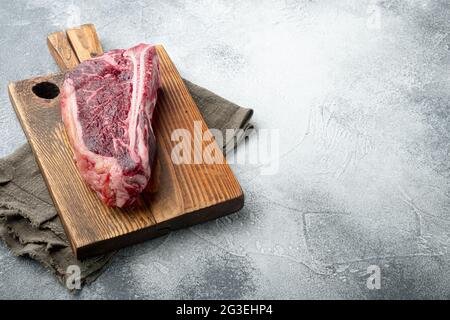 Set de steak Club vieilli à base de viande fraîche brute, sur fond de pierre grise, avec espace pour le texte Banque D'Images