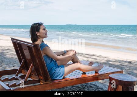 Belle jeune femme asiatique se détendant et bronzer sur un salon en bois sur la plage dans la mer tropicale. Concept été et vacances Banque D'Images