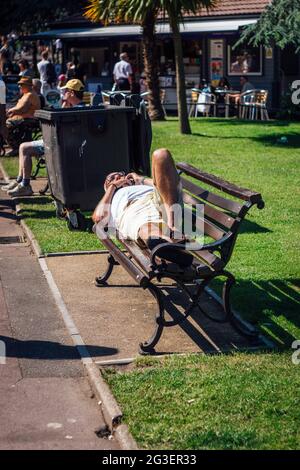 Un homme plus âgé se bronzer sur un banc dans les jardins de Bournemouth, au Royaume-Uni. Banque D'Images