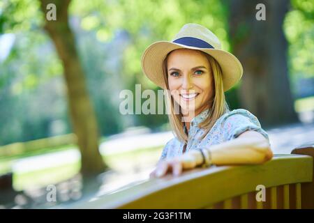 Une jolie fille heureuse assise sur un banc Banque D'Images