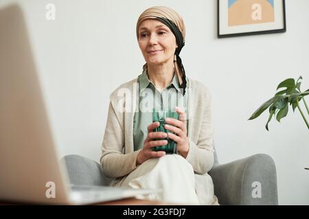 Portrait spontané d'une femme adulte portant un foulard tout en regardant l'écran d'un ordinateur portable, les appels vidéo et le concept de distance sociale, l'espace de copie Banque D'Images