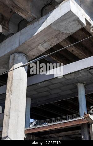 Structure en béton armé de la voie de passage d'autoroute. Fissures des poutres en béton sous le pont. Vue de bas en bas. Banque D'Images